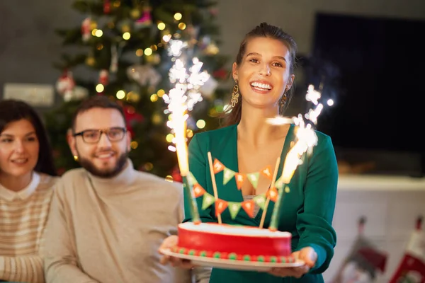 Group of friends celebrating Christmas at home with fancy cake