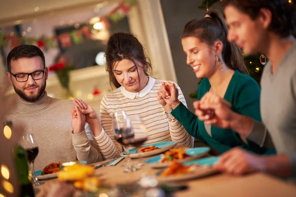 Groep vrienden bidden over Kerstmis Thanksgiving tafel thuis — Stockfoto