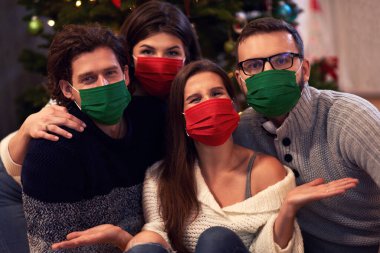 Evde Noel 'i kutlayan maskeli bir grup arkadaş.