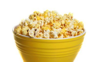 Beyaz arka planda izole edilmiş sarı bir kasede patlamış mısır.