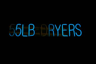 Neon sign in a laundromat. 55 lb dryers. Neon lettering. 100 pound dryers sign. Night bright signboard, glowing light banner. clipart