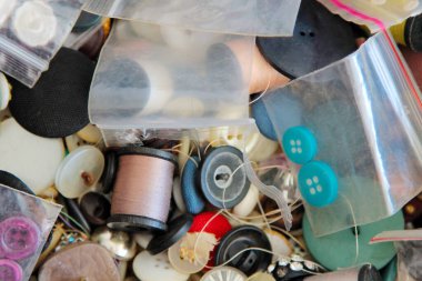 Düğmeler. Kıyafet tamiri için çeşitli düğmelerin koleksiyonu. Renkli düğmeler ve ipliklerle dolu eski bir dikiş kutusu. Dikiş seti. Terzi çantası. Kıyafet Tamiri. Dik şunu. Renkli giysi düğmeleri. İplik. Dikiş