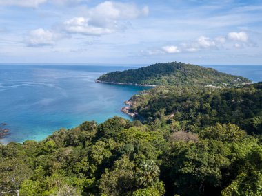 İnsansız hava aracının kuş bakışı görüntüsü denizin maviliğine karşı tropikal ormanlarla kaplı bir dağ sırasını vuruyor..