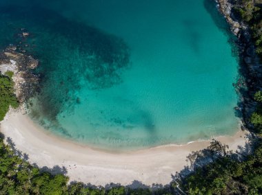 İnsansız hava aracının hava görüntüsü Phuket 'in batı kıyısındaki dağlarda gizlenmiş küçük bir koydan kristal berrak su açığa çıkarıyor..