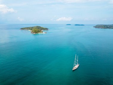 Phuket denizinin çivit mavisi içinde sakince demirlemiş büyük beyaz bir yelkenli..