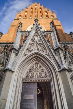 Krakow'daki Holy Trinity Bazilikası girişine karşı günbatımı ışınları mavi gökyüzünde. Polonya