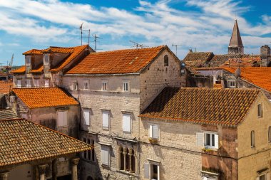 Trogir, Hırvatistan - Güneşli havalarda çatıları döşemeli ve üzerinde mavi gökyüzü olan eski şehir binaları