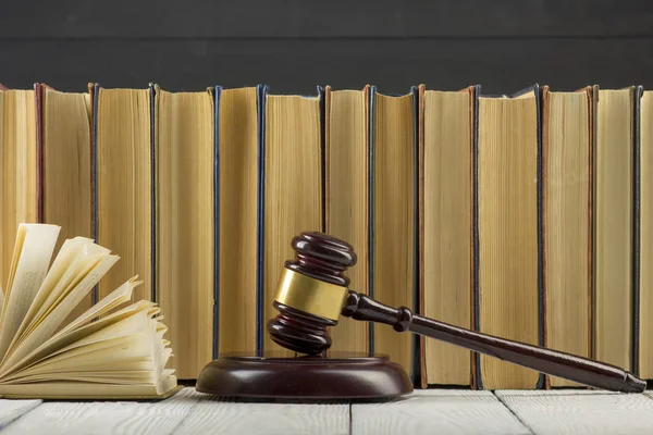 Legal Law concept - Open law book with a wooden judges gavel on table in a courtroom or law enforcement office.