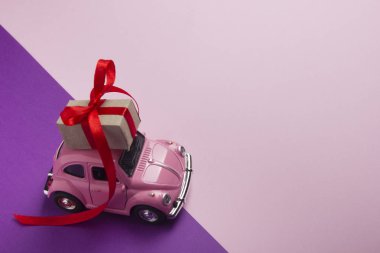 Pembe retro oyuncak araba hediye kutusu pastel arka plan üzerinde teslim. Üstten Görünüm