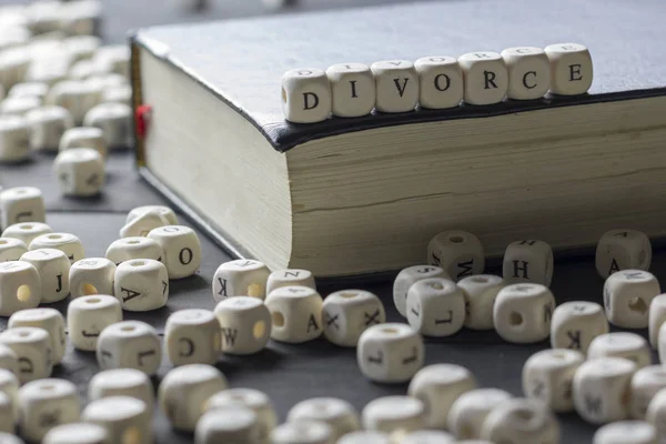 Parola - Divorzio composto da lettere in legno sul tavolo con fedi nuziali . — Foto Stock