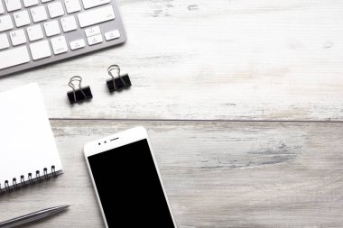 Bilgisayarlı beyaz masa ofisi, akıllı telefon ve bir fincan kahveli diğer iş malzemeleri. Metni kopyalamak için üst görünümü kullan. Desenci çalışma alanı düz masa üzerinde temel elementler yatıyordu
