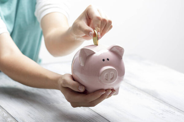 woman hand putting money coin into piggy for saving money wealth and financial concept.