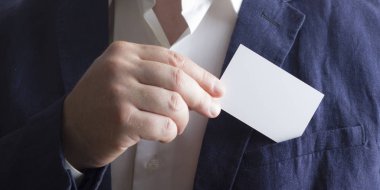 Beyaz arka plan üzerinde beyaz kartvizit tutan el
