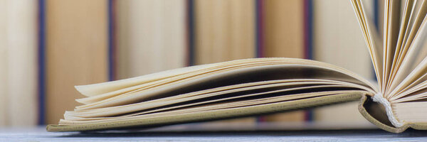 Открытая книга, книги в твердом переплете на деревянном столе. Возвращайся в школу. Копирование пространства