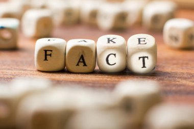 Tahta arka plandaki tahta küplere sahte ve gerçek yazılar.