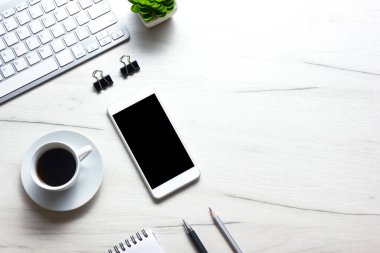 Bilgisayarlı beyaz masa ofisi, akıllı telefon ve bir fincan kahveli diğer iş malzemeleri. Metni kopyalamak için üst görünümü kullan. Desenci çalışma alanı düz masa üzerinde temel elementler yatıyordu