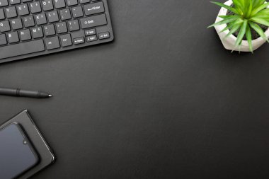 Laptop, akıllı telefon ve bir fincan kahveli diğer iş malzemeleri olan siyah masa ofisi. Metni kopyalamak için üst görünümü kullan. Desenci çalışma alanı düz masa üzerinde temel elementler yatıyordu