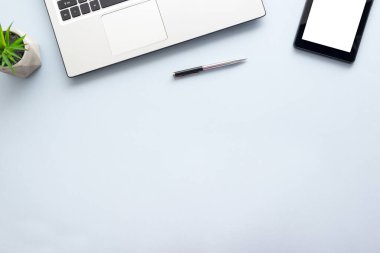 Dizüstü bilgisayarı, akıllı telefonu ve bir fincan kahveli diğer iş malzemeleri olan mavi masa ofisi. Metni kopyalamak için üst görünümü kullan. Desenci çalışma alanı düz masa üzerinde temel elementler yatıyordu