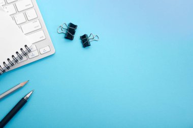 Dizüstü bilgisayarı, akıllı telefonu ve bir fincan kahveli diğer iş malzemeleri olan mavi masa ofisi. Metni kopyalamak için üst görünümü kullan. Desenci çalışma alanı düz masa üzerinde temel elementler yatıyordu