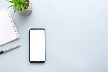 Dizüstü bilgisayarı, akıllı telefonu ve bir fincan kahveli diğer iş malzemeleri olan mavi masa ofisi. Metni kopyalamak için üst görünümü kullan. Desenci çalışma alanı düz masa üzerinde temel elementler yatıyordu