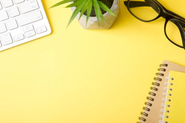 Laptop, akıllı telefon ve bir fincan kahveli diğer iş gereçleri olan sarı masa ofisi. Metni kopyalamak için üst görünümü kullan. Desenci çalışma alanı düz masa üzerinde temel elementler yatıyordu