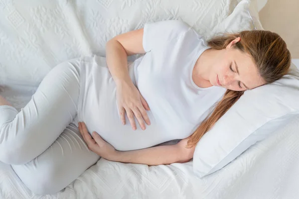 Giovane Donna Incinta Casa Appoggiata Sul Divano Bianco Abbracciando Pancia — Foto Stock