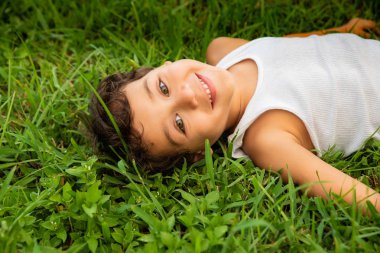 arka bahçesinde üzerinde oynarken, çim üzerinde yalan, gülerek mutlu çocuk