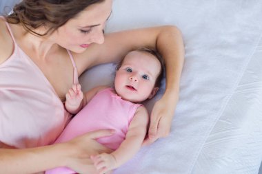 güzel genç anne 4 aylık bebek kızı yatak - mutlu annelik kavramı ile sarılma