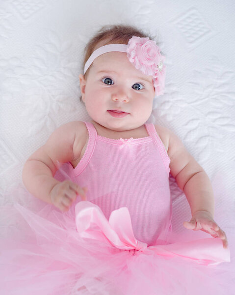 cute baby girl 4 months old resting on the bed - little tutu dancer