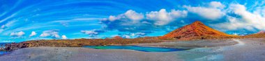 Kanarya adası, Lanzarot 'taki deniz kıyısındaki kırmızı dağ ve yeşil su birikintisi. İspanya plajları. Timanfaya Ulusal Parkı' nda eşi benzeri olmayan etkileyici ve manzaralı volkanik doğa.