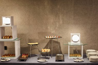 Bir modern ziyafet masada çeşitli atıştırmalıklar gri bir duvara yuvarlak lambalar tarafından aydınlatılmış bir gri masa örtüsü ile kaplı