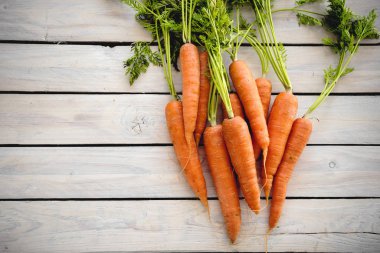 Yemek pişirmek için bir ham madde olarak ahşap bir masa üzerinde yeşil bir sapı ile renkli havuç