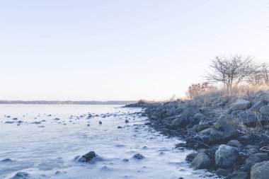 Sabah erken Sunrise bir sahil şeridi üzerinde donmuş deniz kayalarda