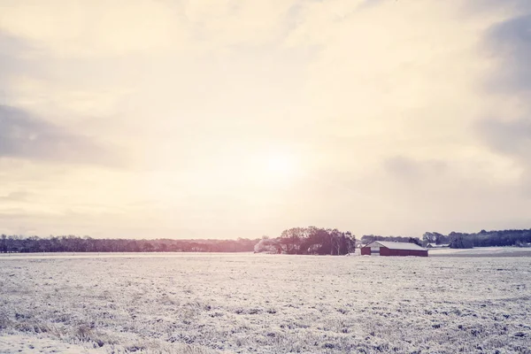 农村冬季景观与红色谷仓在田野上覆盖着雪在日出 — 图库照片