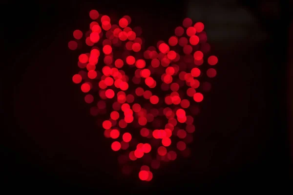 バレンタインの日に暗い背景に赤い色で光沢のあるボケ ライトから作られた心 — ストック写真