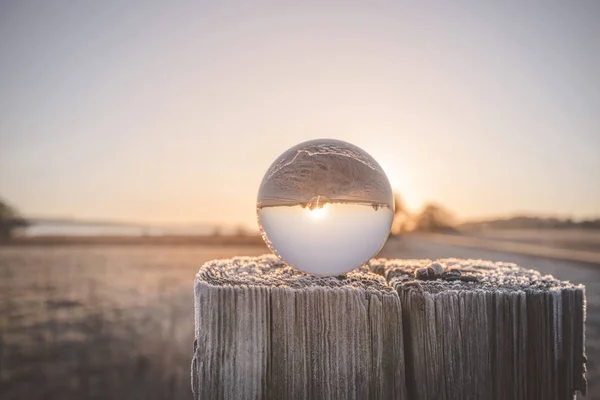 在冬天的一个寒冷的早晨在日出的木柱上的玻璃球 — 图库照片