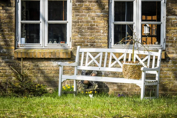 Vit Bänk Utanför Ett Gammalt Tegelhus Med Påskliljor Blommar Våren — Stockfoto