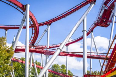 Rollercoaster eğrileri ve mavi gökyüzü altında döngüler ile kırmızı renklerde