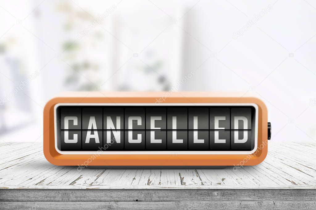 Cancelled message on a retro alarm clock in a bright room with a weathered wooden table