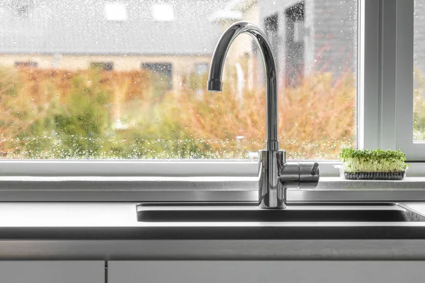 Chrom Wasserhahn Einer Küchenspüle Mit Feuchtem Fenster Hintergrund lizenzfreie Stockfotos