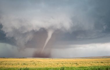 A thin cone tornado spins over the open landscape of the Great Plains. clipart