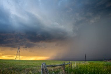 A storm drops a torrent of rain over the rural countryside at sunset. clipart