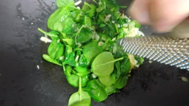 Çinli bir wok içinde taze ıspanak Kavurma ve baharat Hindistan cevizi bir öğütücü ile ekleme