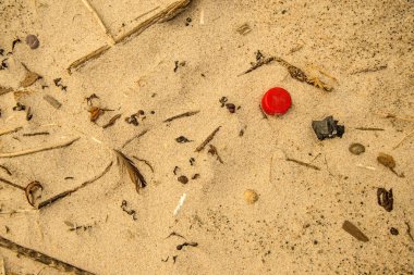 bir plajda, kırmızı kapak plastik atık