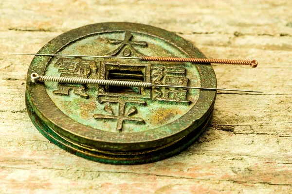 Acupuncture needles on antique Chinese coin — Stock Photo, Image