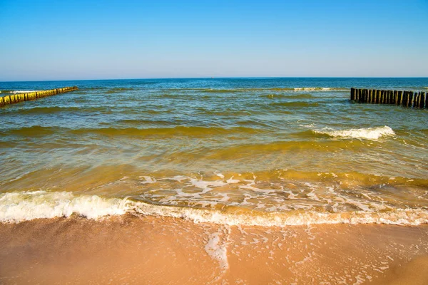 Baltic Sea with groins and surf and blue sky — Stock Photo, Image