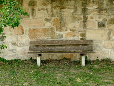 Eski bir manastır duvarındaki park bankında.
