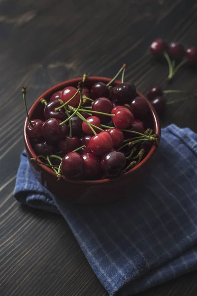 Des cerises. Cerise. Cerises dans un bol de couleur et une serviette de cuisine . — Photo