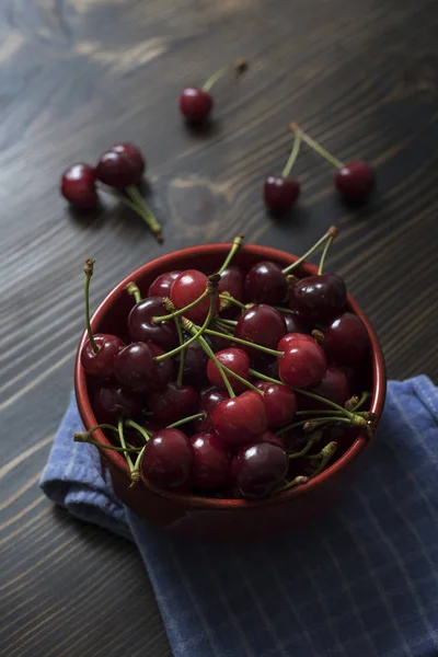 Des cerises. Cerise. Cerises dans un bol de couleur et une serviette de cuisine . — Photo