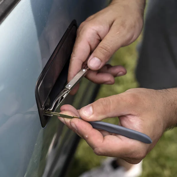 Masculino mecânico segurando Lockpicker para abrir a porta do carro — Fotografia de Stock